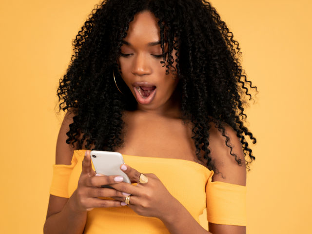 A young woman surprised while looking at a FinalFYI message on her mobile phone